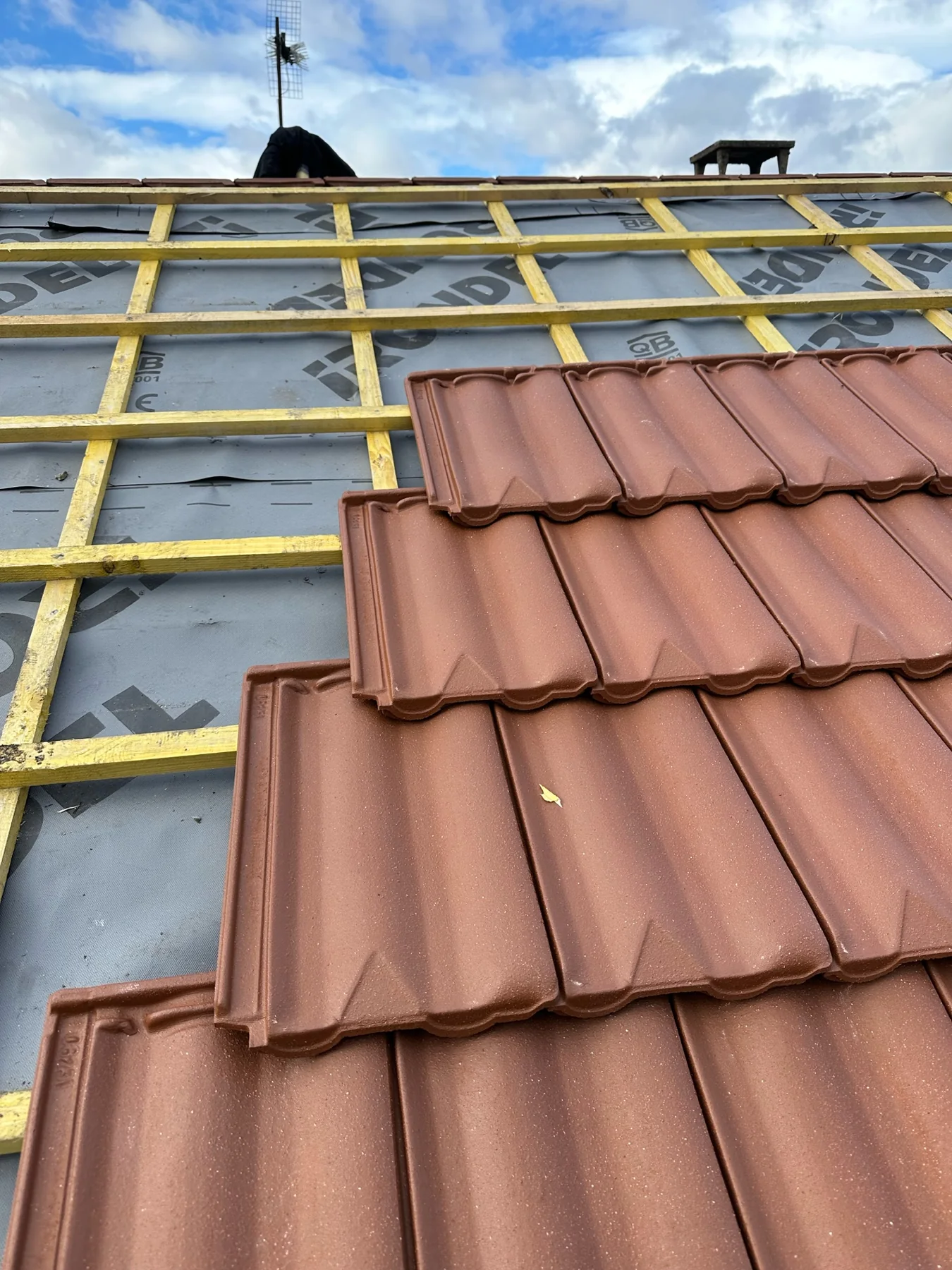 Pose de tuiles neuves pendant une rénovation de toiture